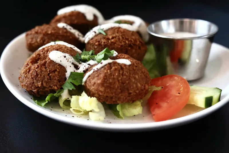 Falafel plate with garlic-yogurt tahini, fresh greens, tomato and cucumber at Leymoon Kitchen